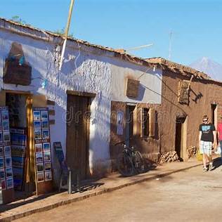 Turistas y locales recorriendo la calle del centro histórico de San Pedro de Atacama, con arquitectura de adobe y ambiente cultural autentic Chile.
